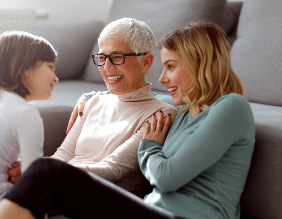 A grandmother, mother and child all on the couch smiling